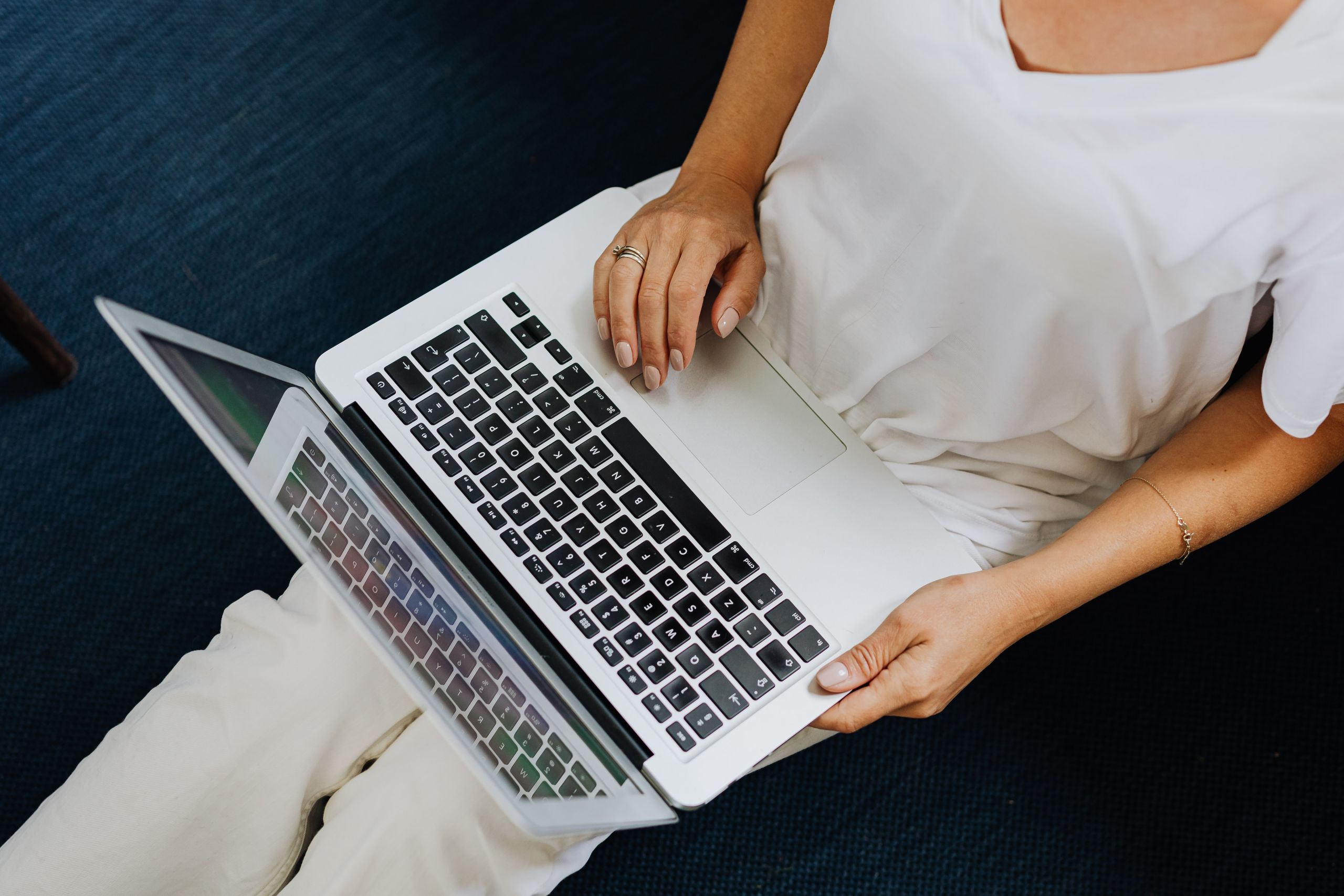 Overhead shot of a person using a laptop on a dark blue carpeted floor.